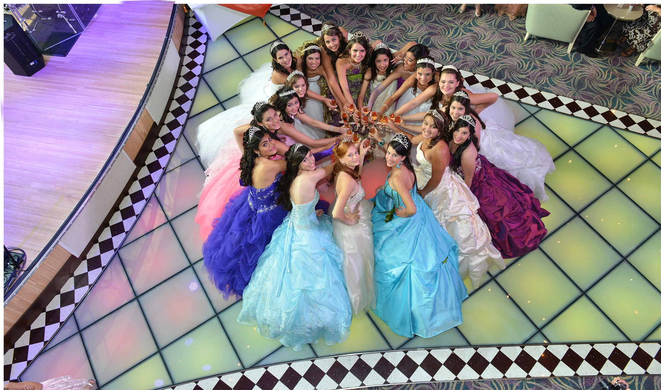 Quinceañeras in colorful gowns gathered together during a gala celebration