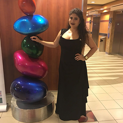 Standing in a black dress beside a colorful balloon sculpture.